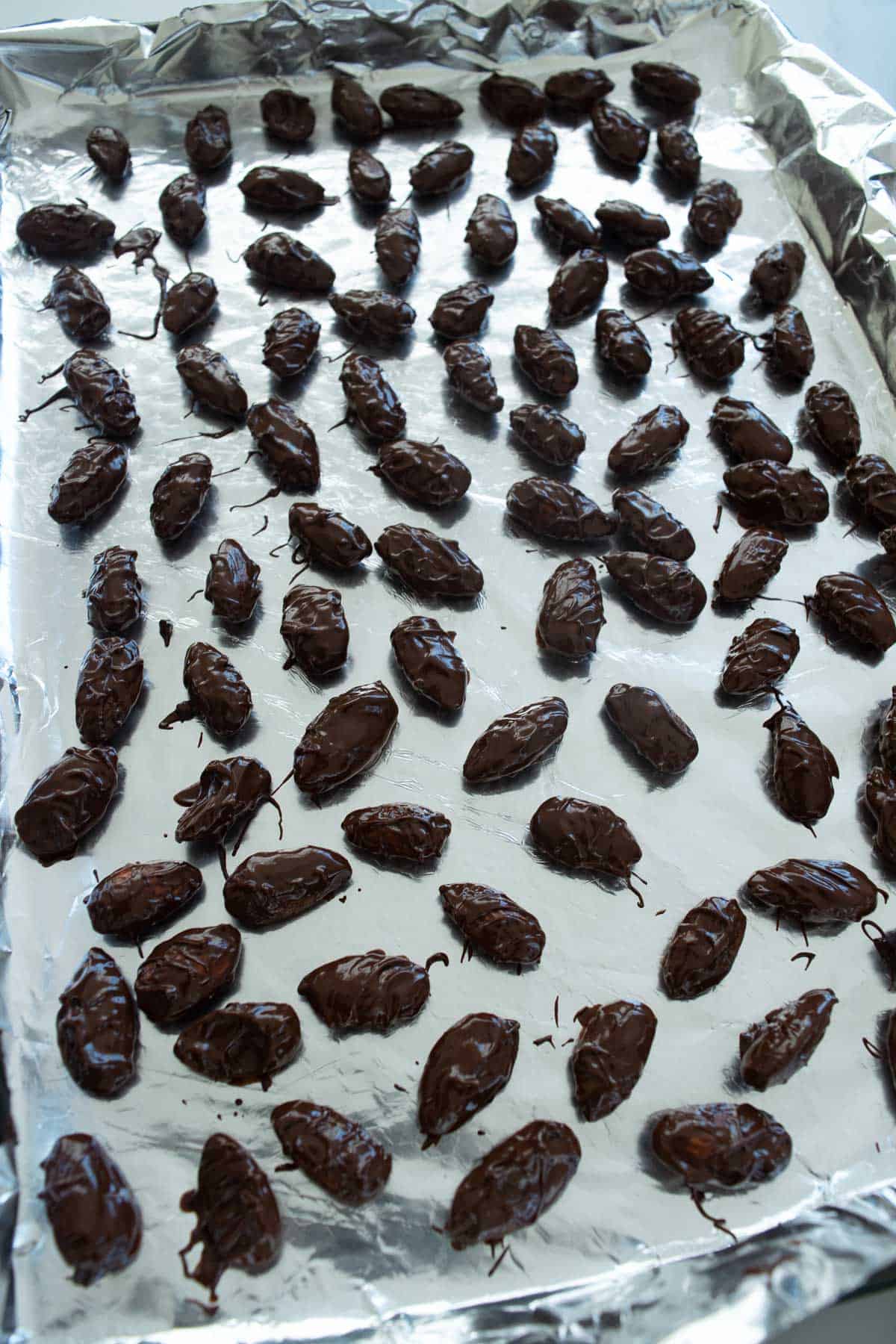 Chocolate covered almonds on a sheet pan.