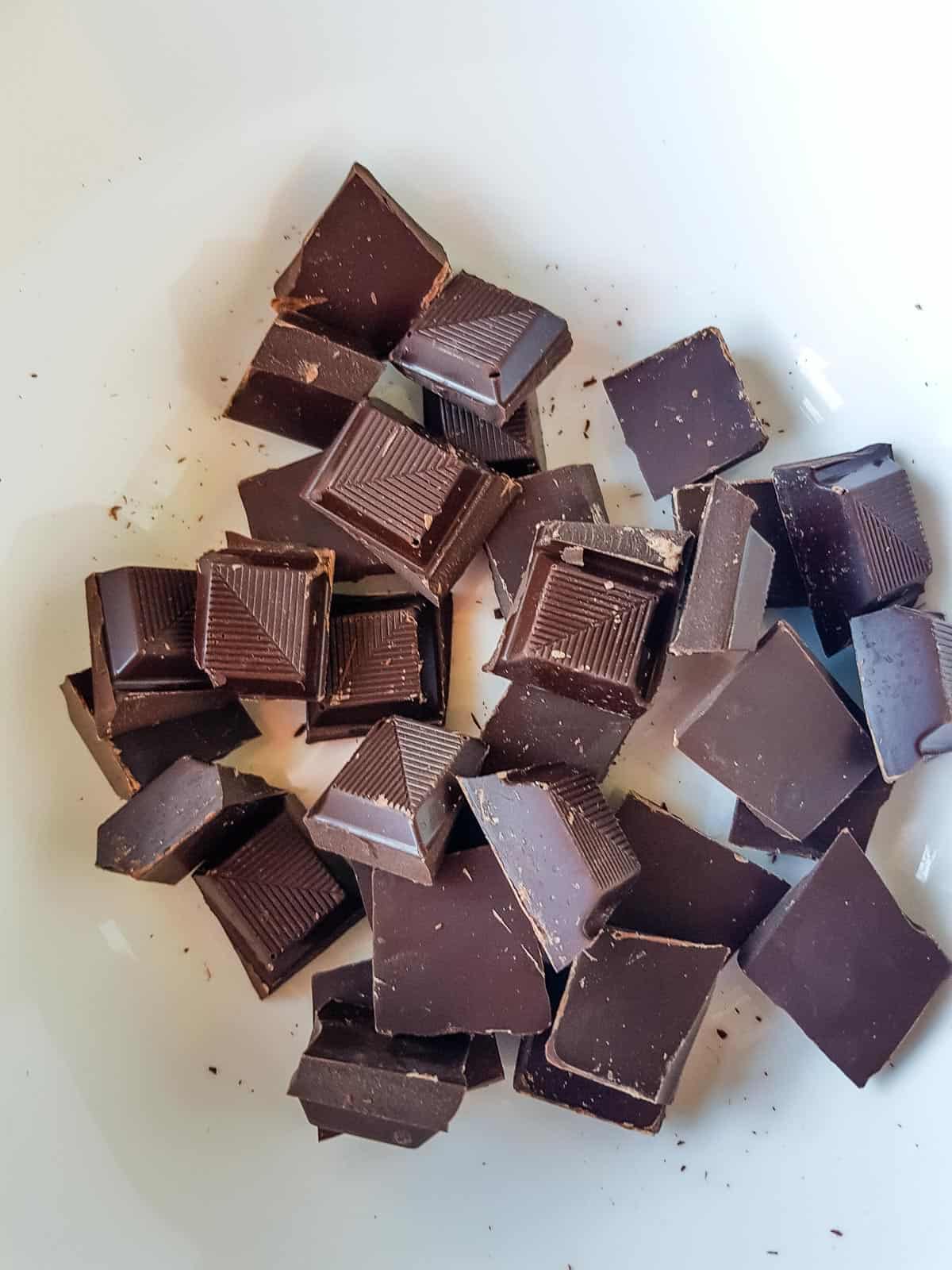 Dark chocolate squares in a bowl.