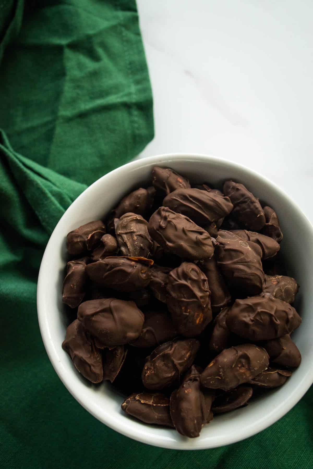 Dark chocolate covered almonds in a bowl.