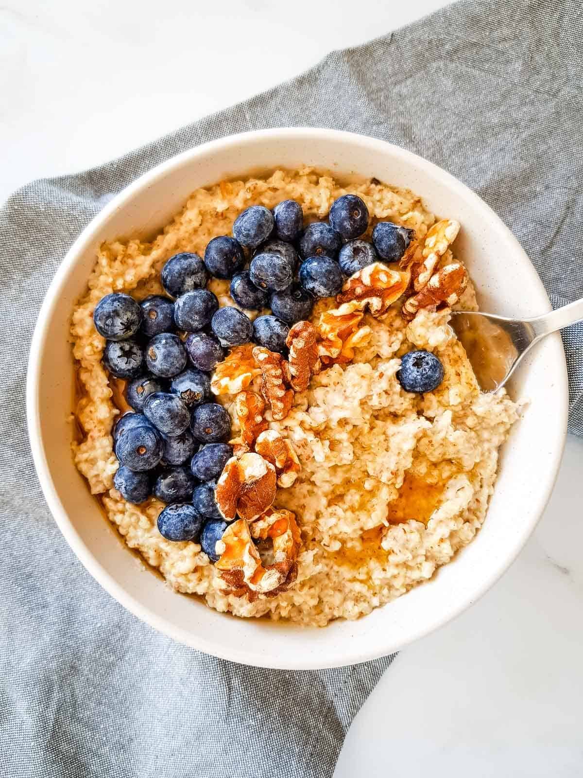 Flaxseed oatmeal in a bowl, with a spoon inserted into it.