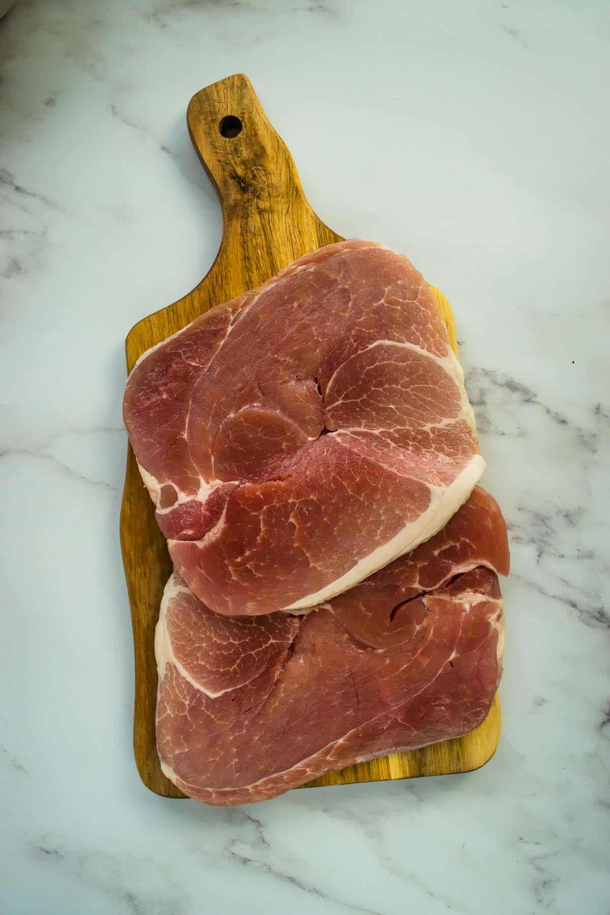 Raw gammon steaks on a chopping board.