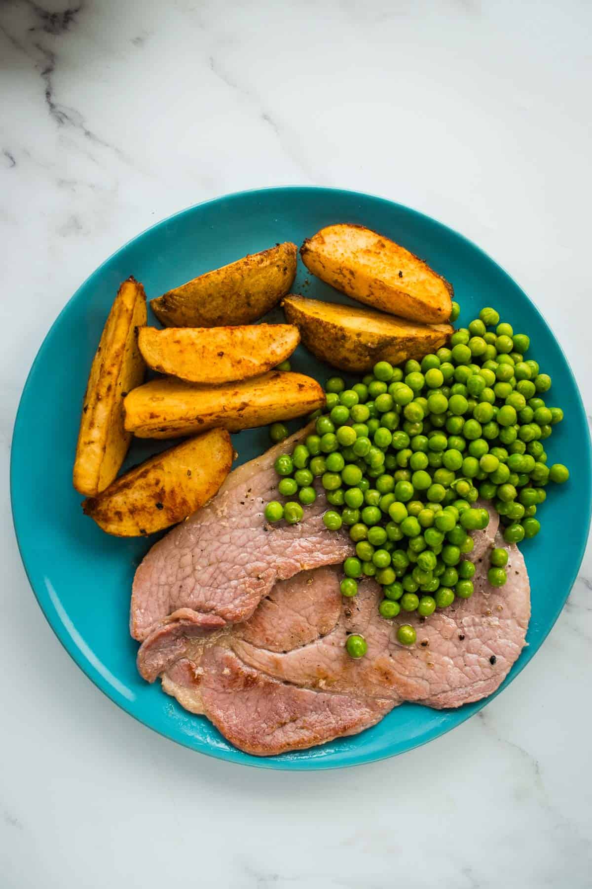 Ham steaks with peas and potatoes.