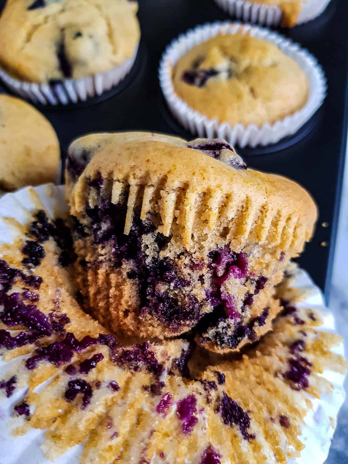 Lemon blueberry muffin with the liner wrapped halfway off.