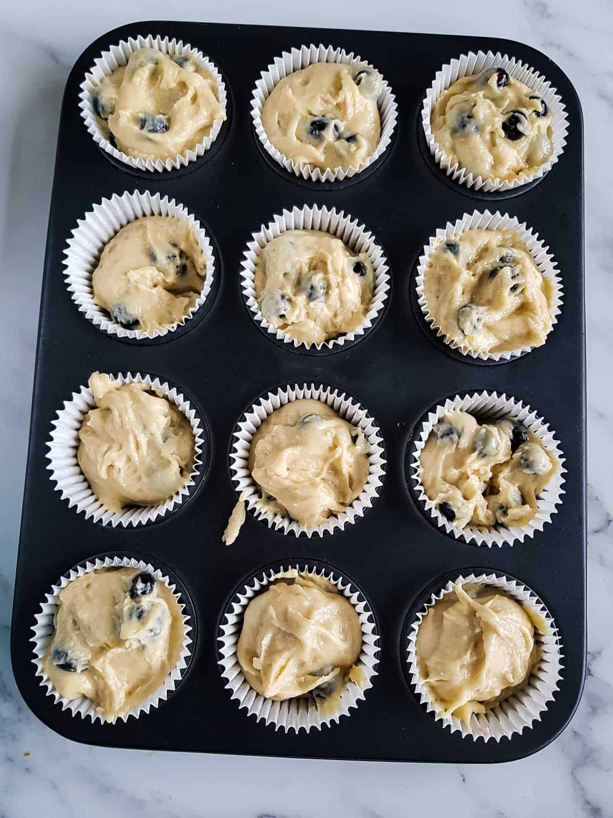 Muffin batter added to lined muffin pan.