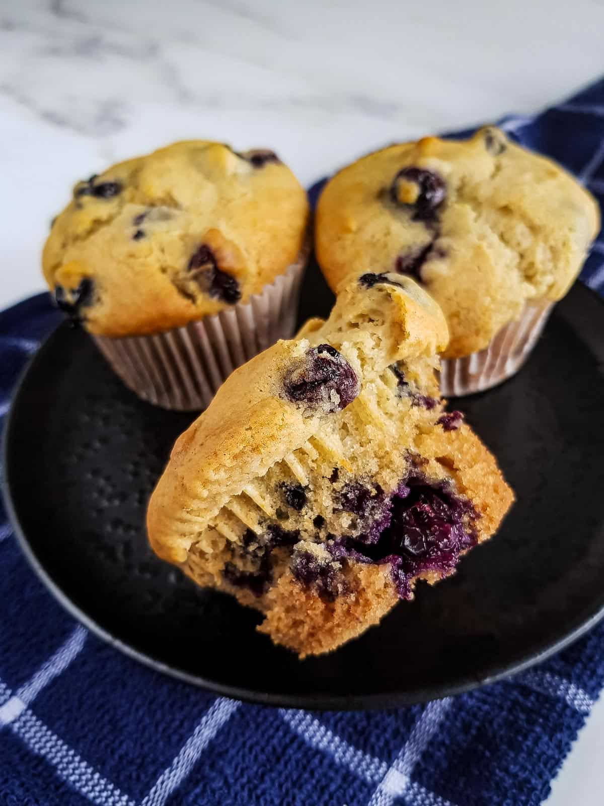 Unwrapped blueberry muffins on a plate.