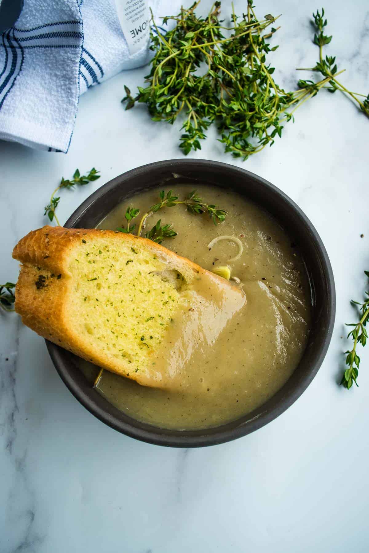 Garlic bread dipped into a bowl of soup.