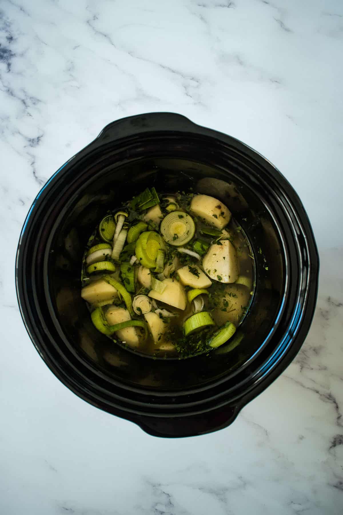 Leeks, potatoes and stock in a slow cooker.