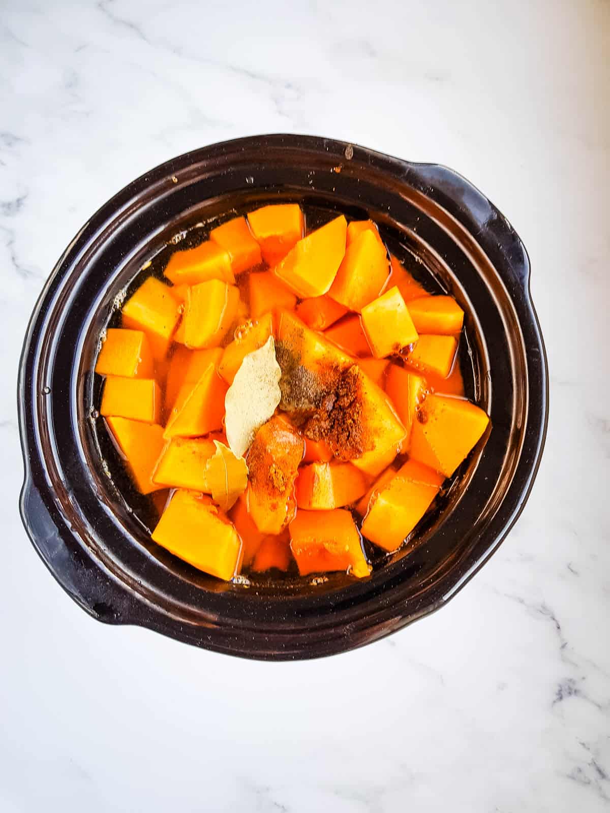 Pumpkin soup ingredients in a slow cooker.