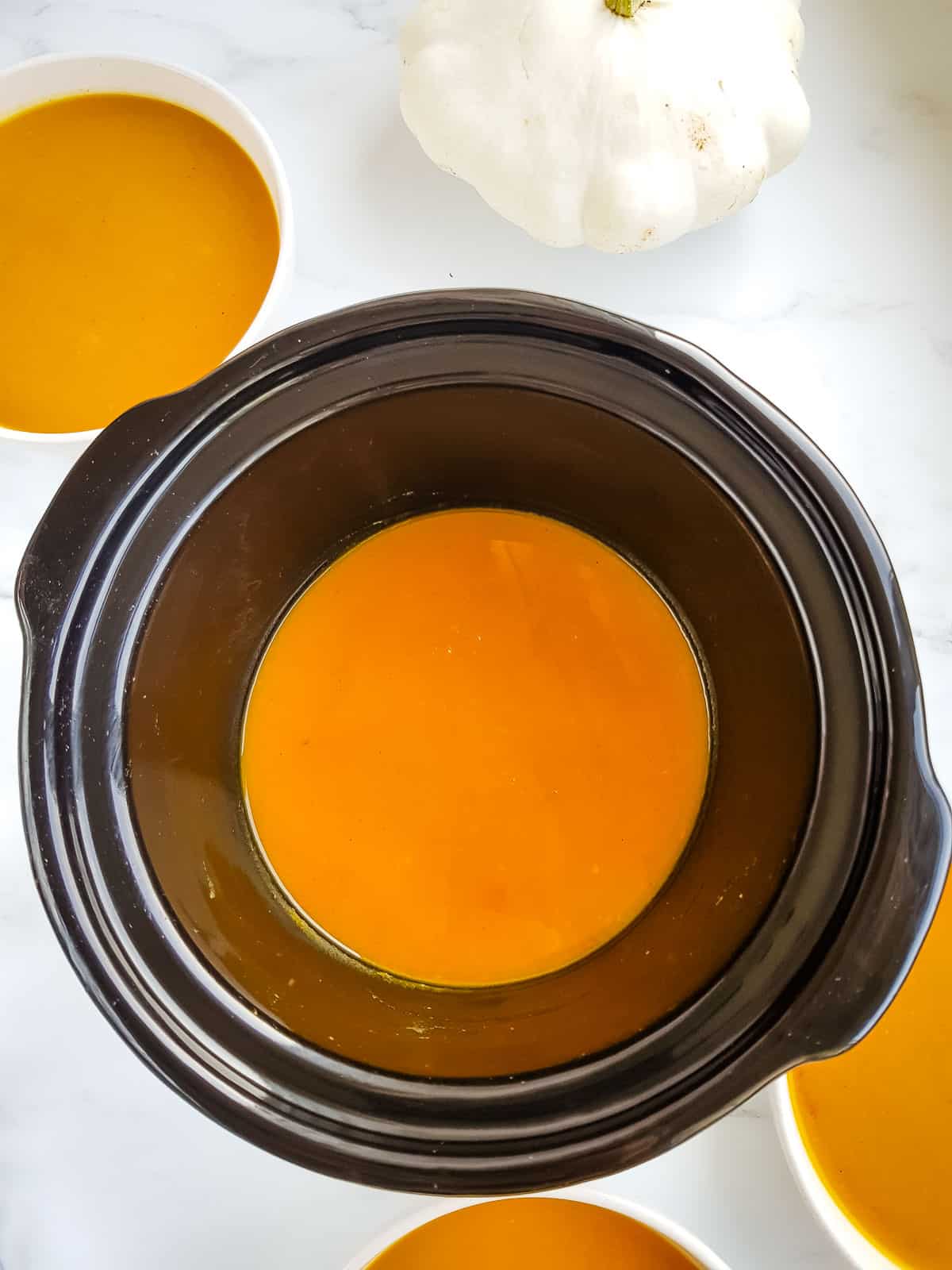 Butternut squash soup in a slow cooker and bowls.