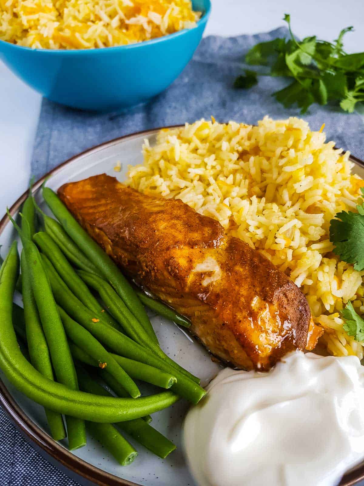 Tandoori salmon on a plate with rice and green beans.