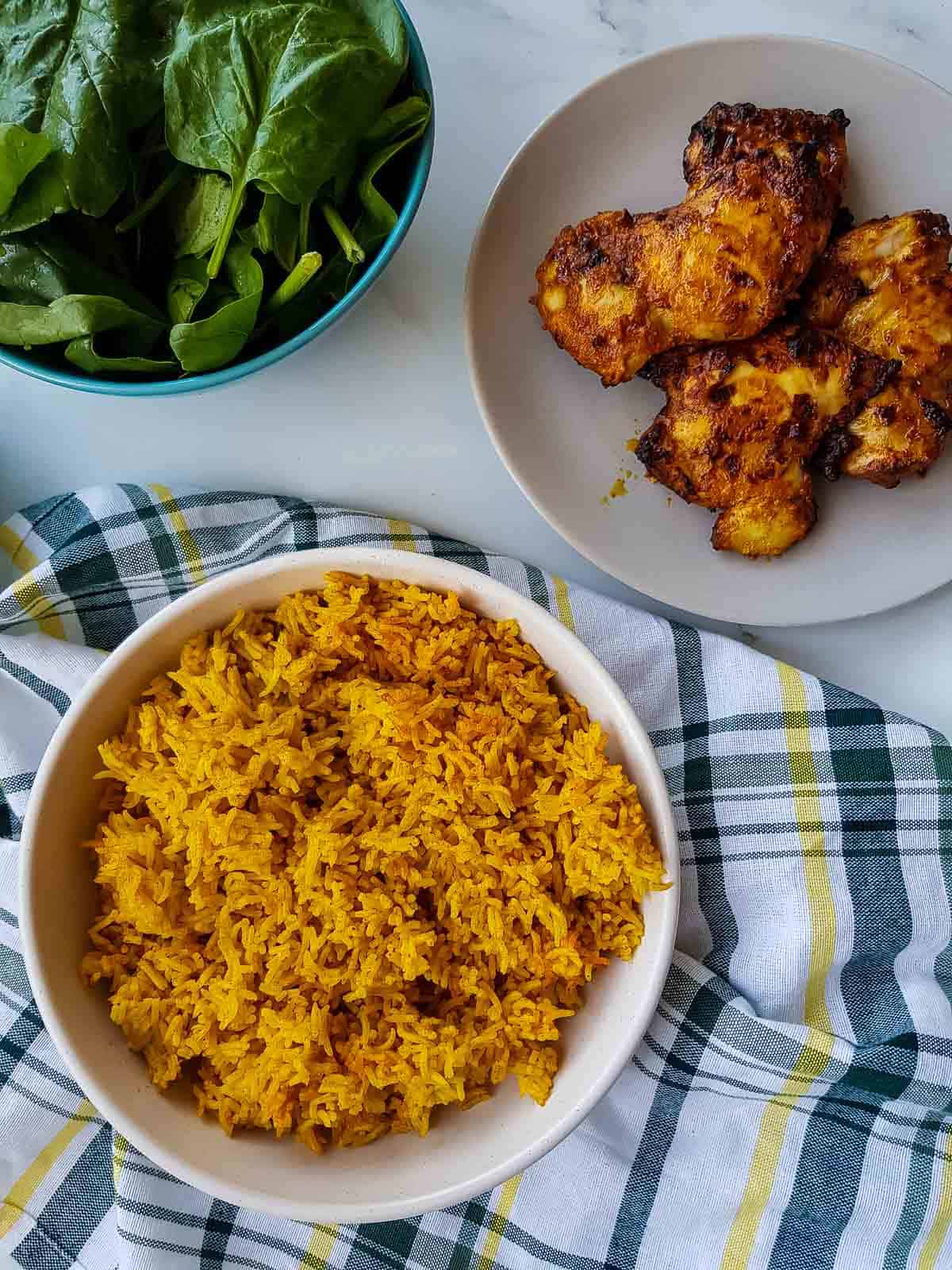 Rice in a bowl with chicken and salad on the side.