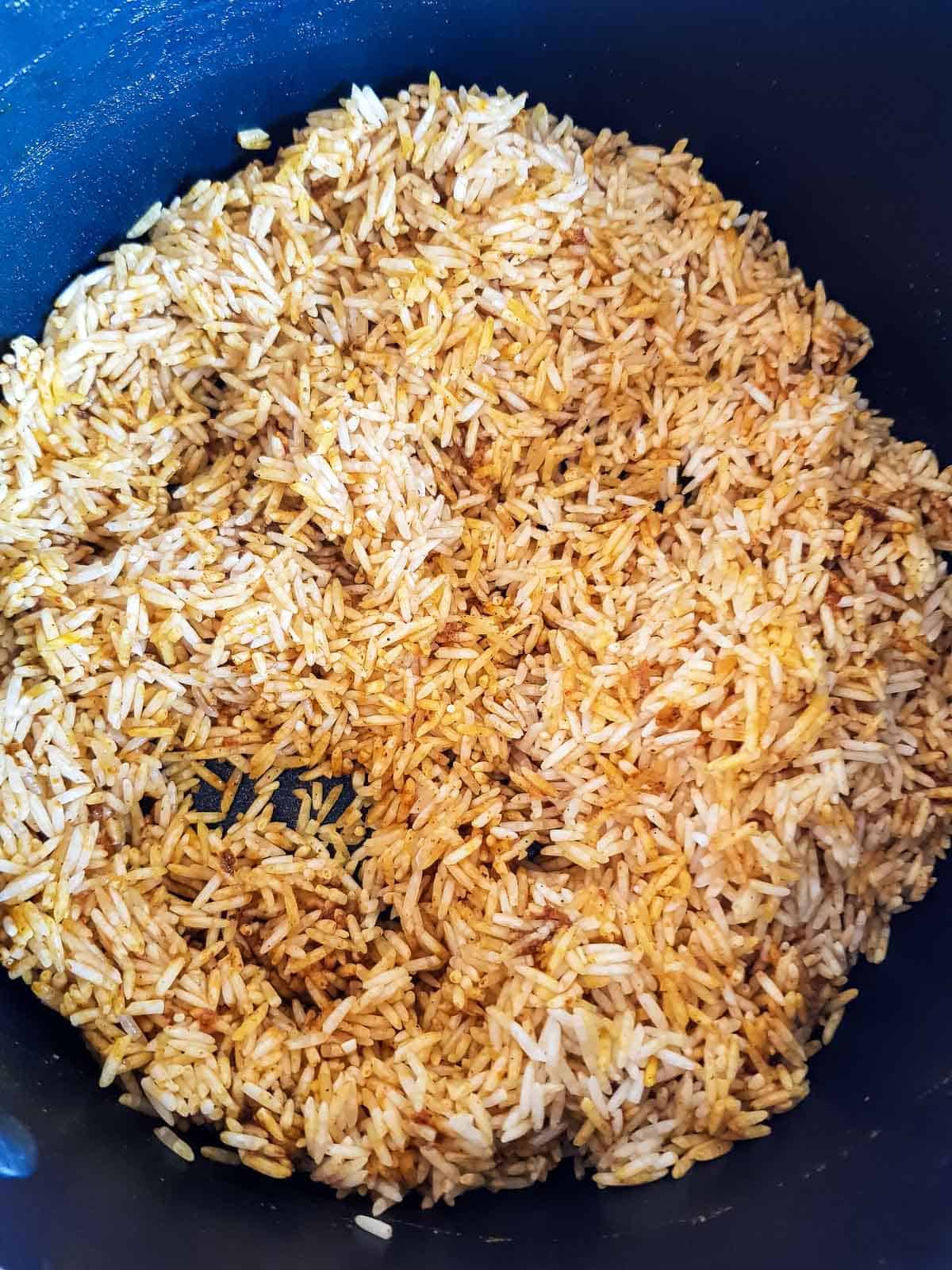 Rice added to the spices in a pot.