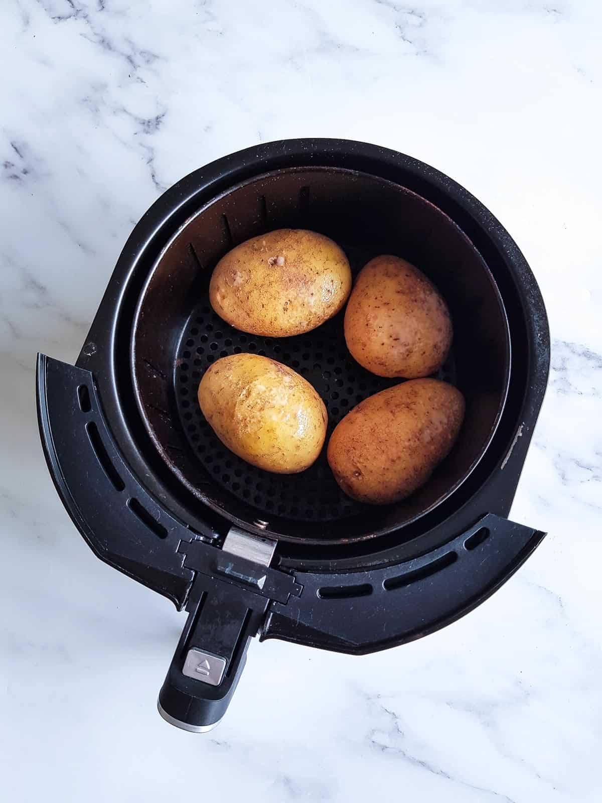 Raw potatoes in an air fryer.