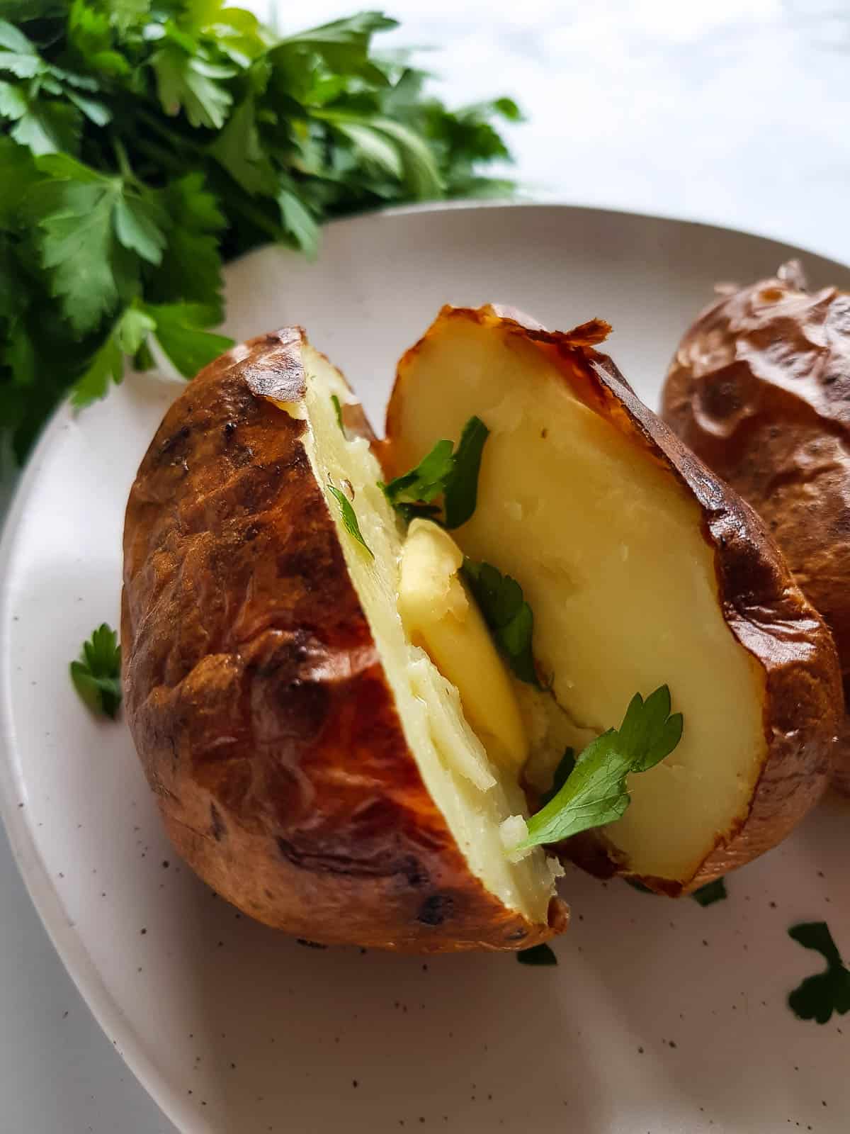 Close up of a baked potato with butter and parsley.