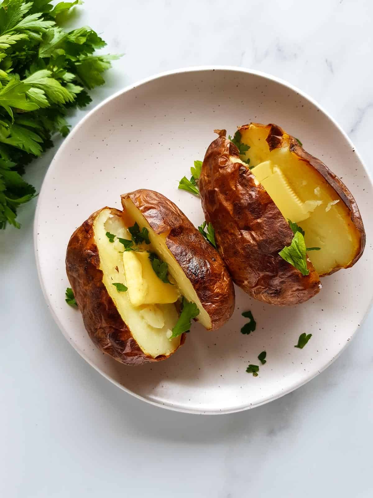 Two baked potatoes on a plate.