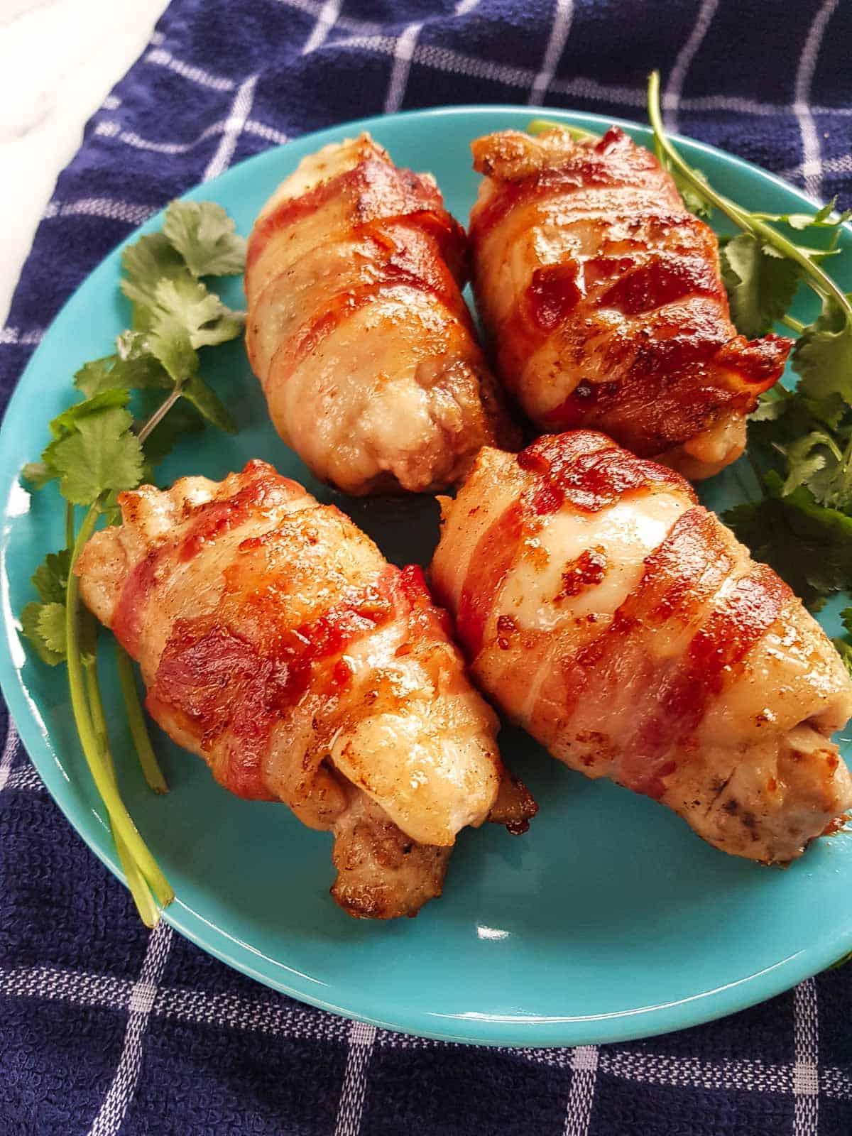 Bacon wrapped chicken thighs on a plate.