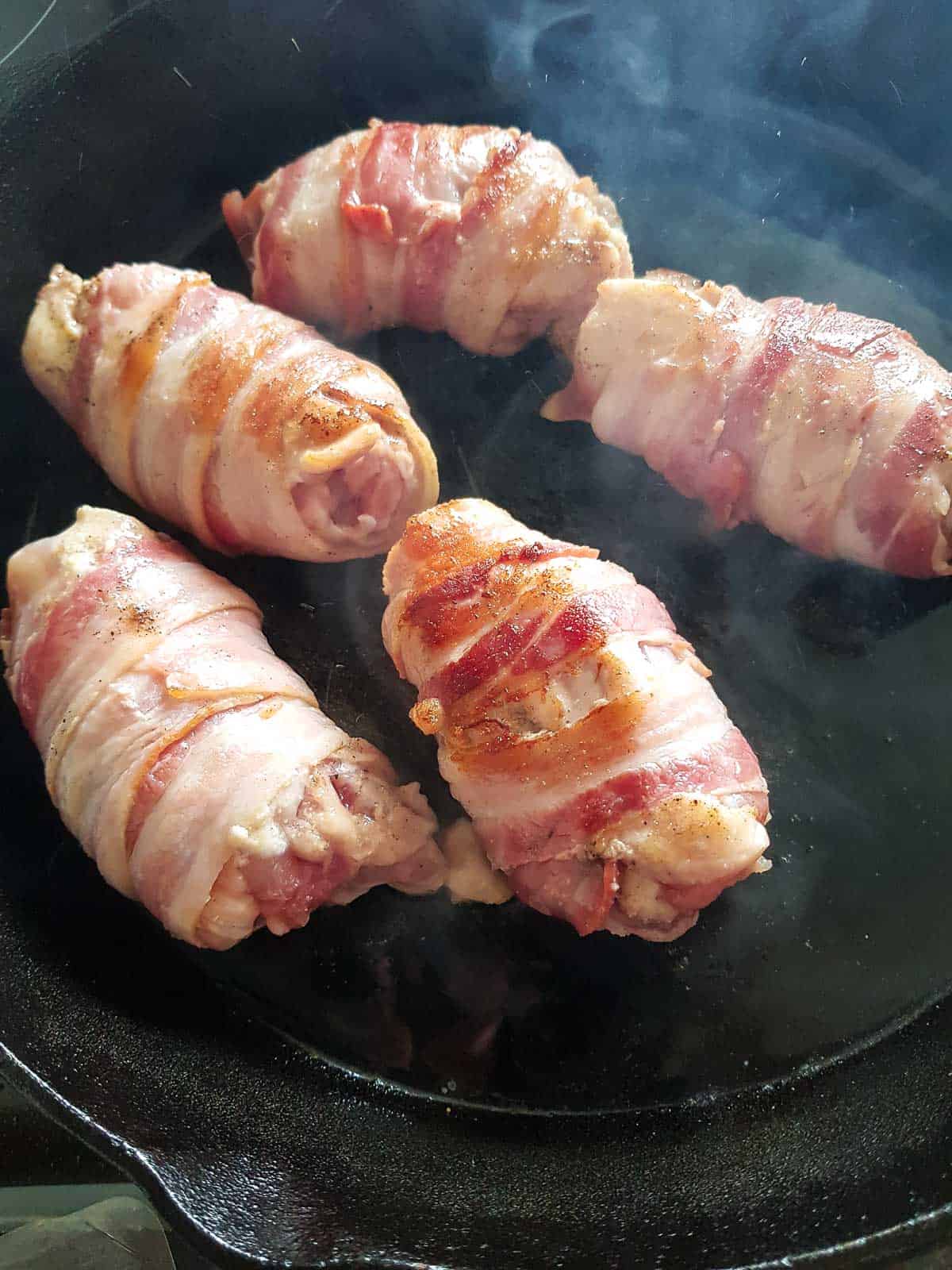 Searing chicken thighs in a cast iron skillet.