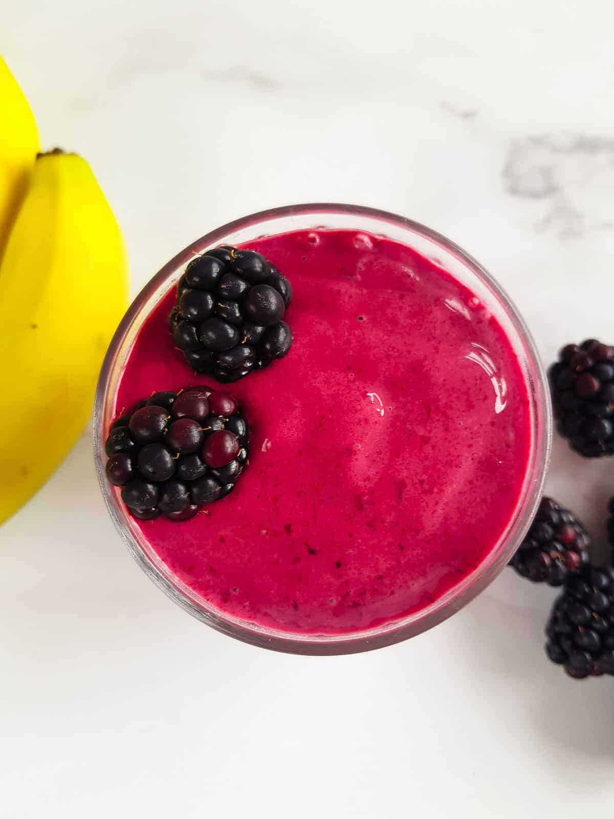 Close up of a glass of blackberry smoothie.