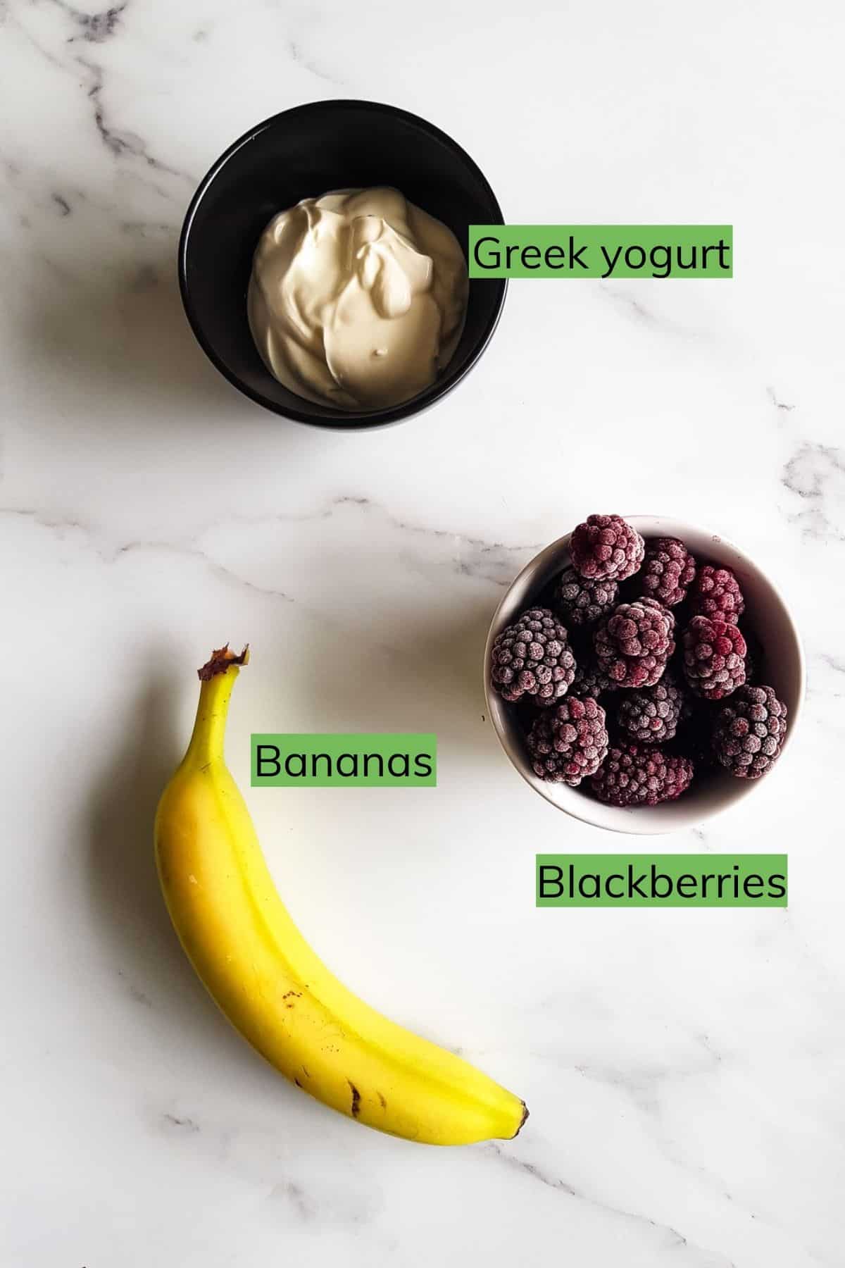 Greek yogurt, blackberries and a banana on a table.