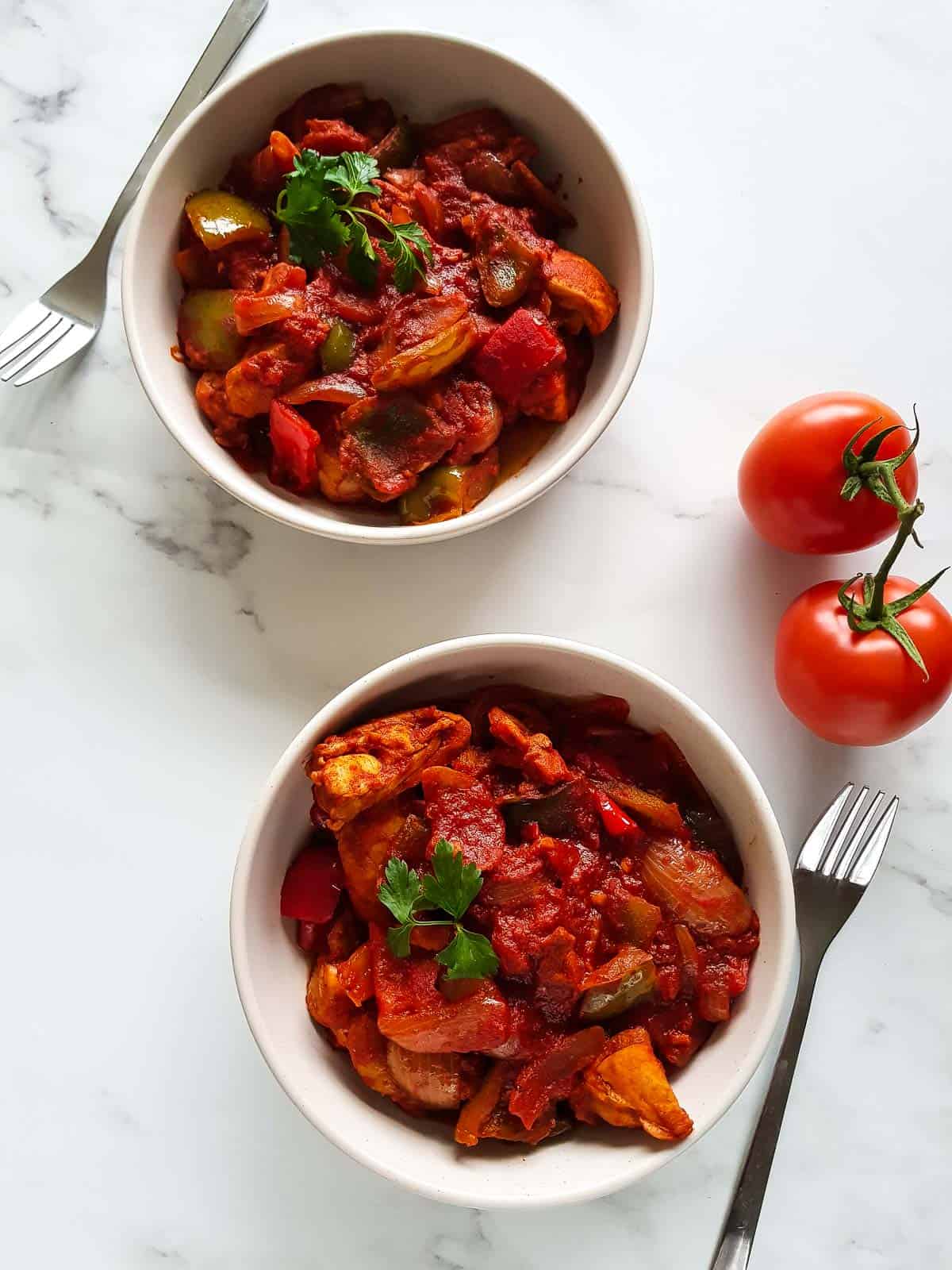 Two bowls of chicken goulash on a table.