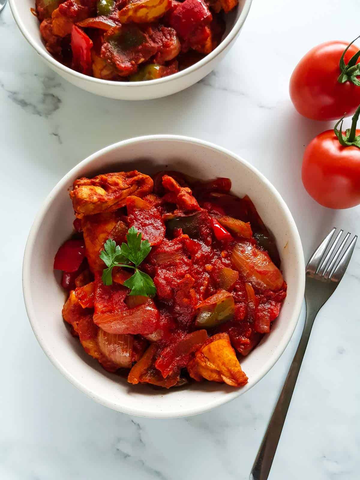 Chicken goulash in a bowl with a fork on the side.