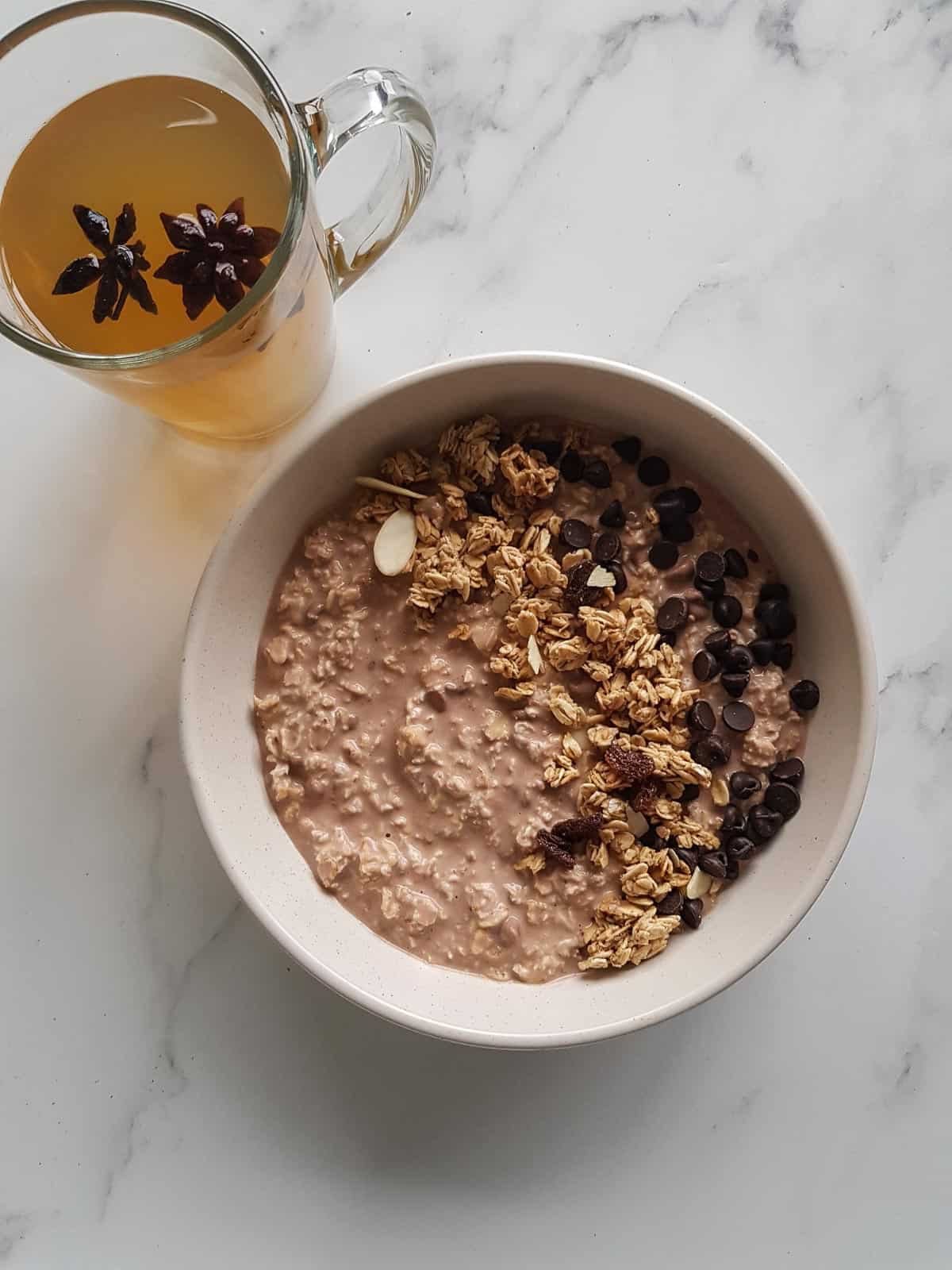 A bowl of chocolate overnight oats, with a cup of tea on the side.