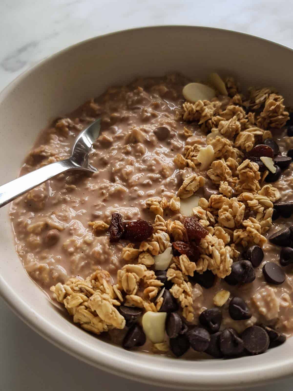 Close up of chocolate overnight oats in a bowl with granola and chocolate chips on top.