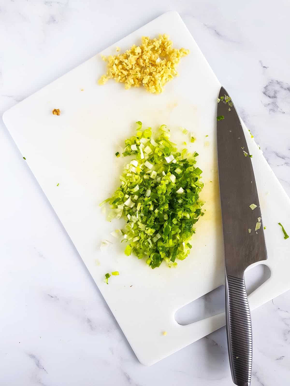 Chopped ginger and scallions on a board.