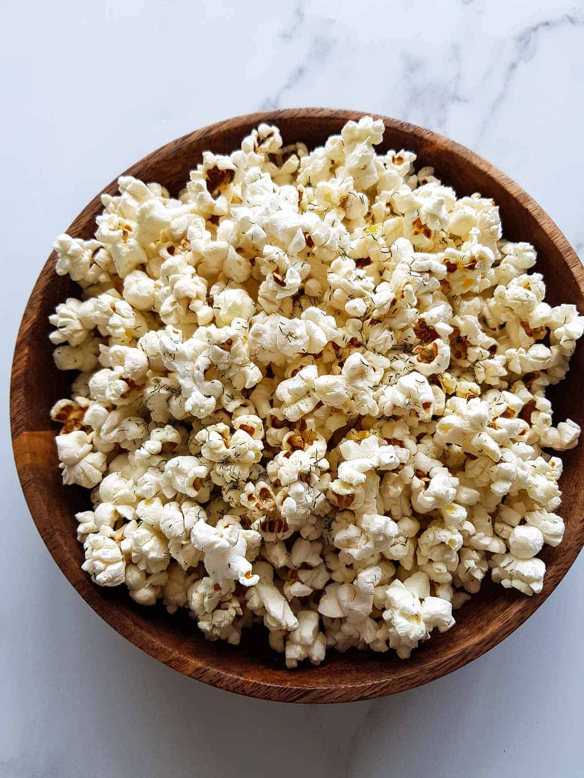 Dill pickle popcorn in a wooden bowl.