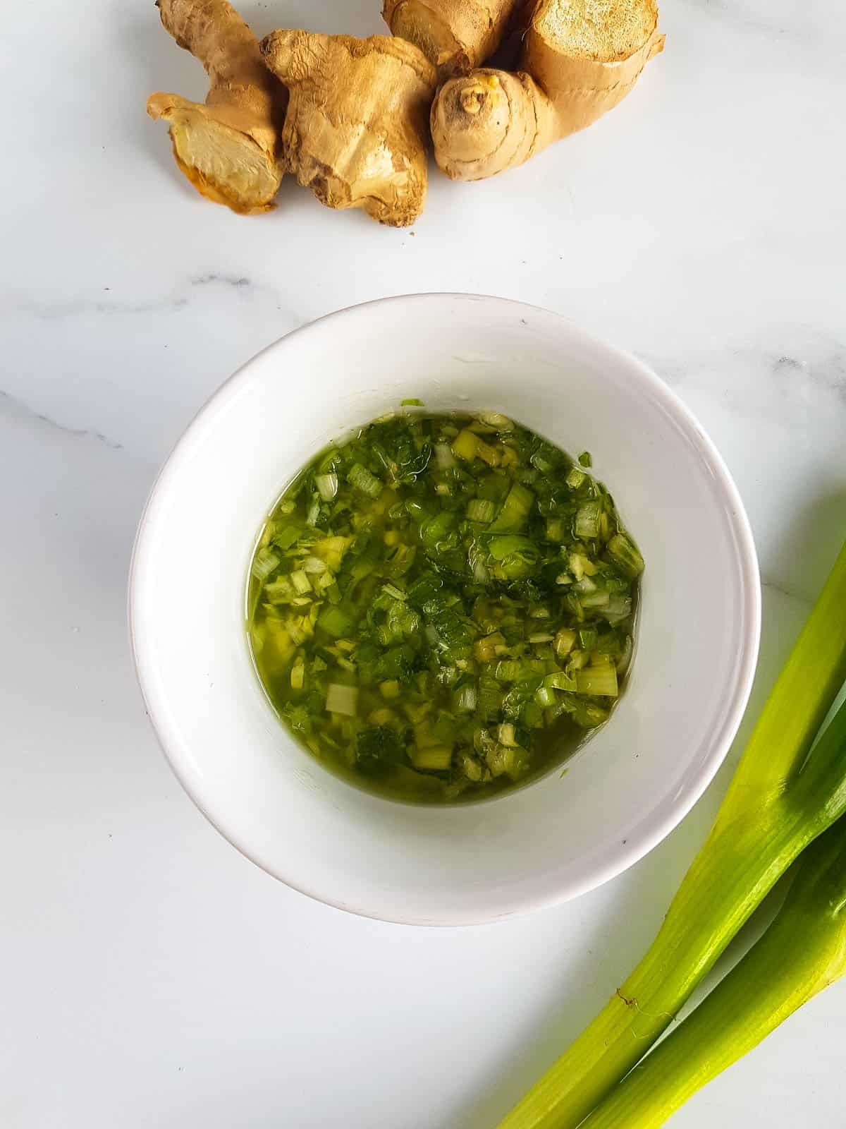 The sauce in a bowl with ginger and scallions on the side.