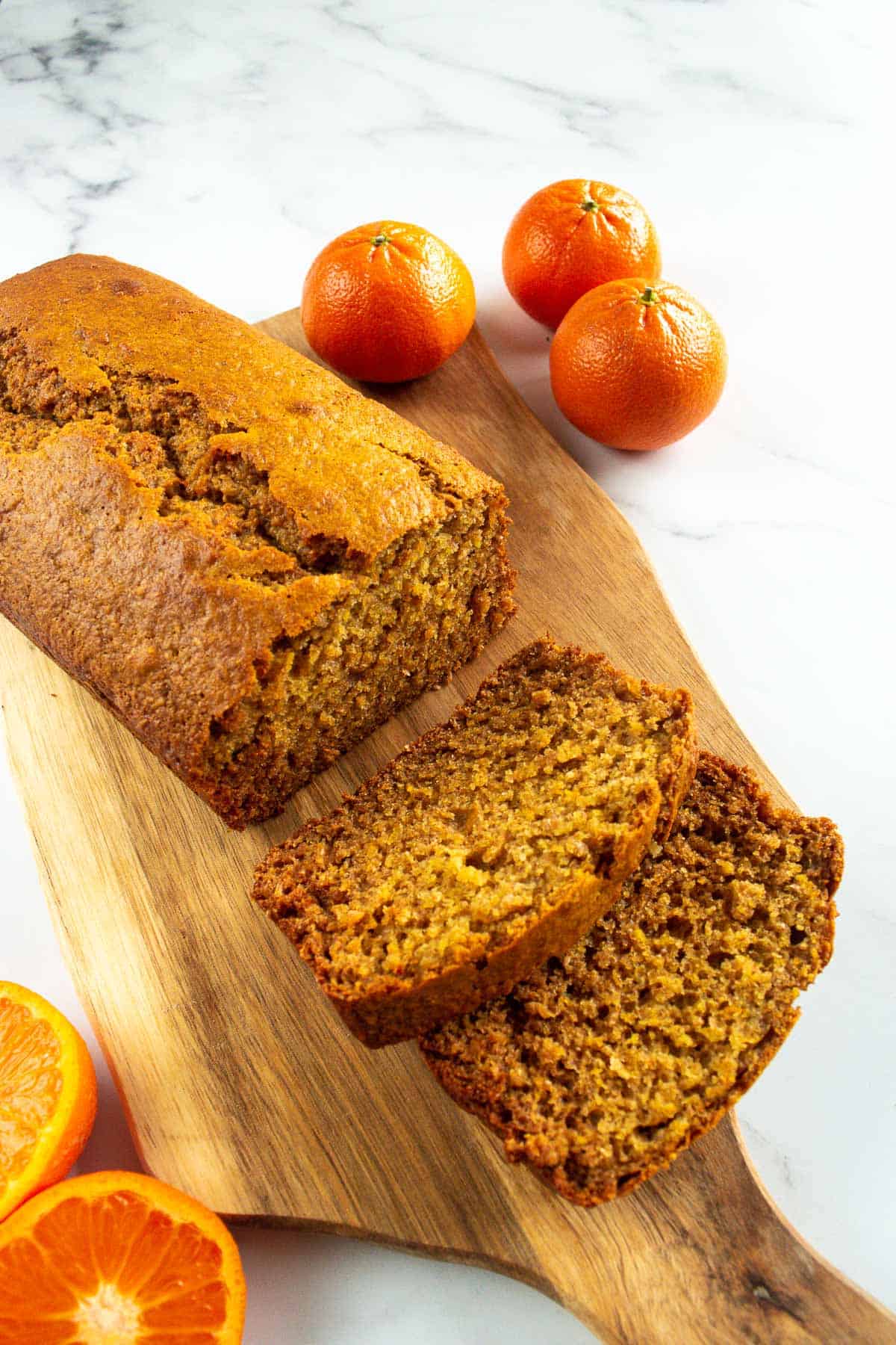 Sliced orange loaf with oranges on the side.