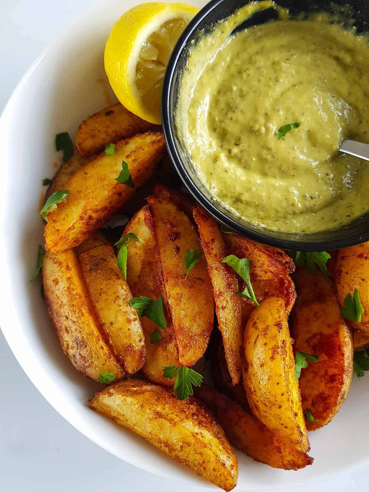 Close up of potato wedges and pesto aioli.