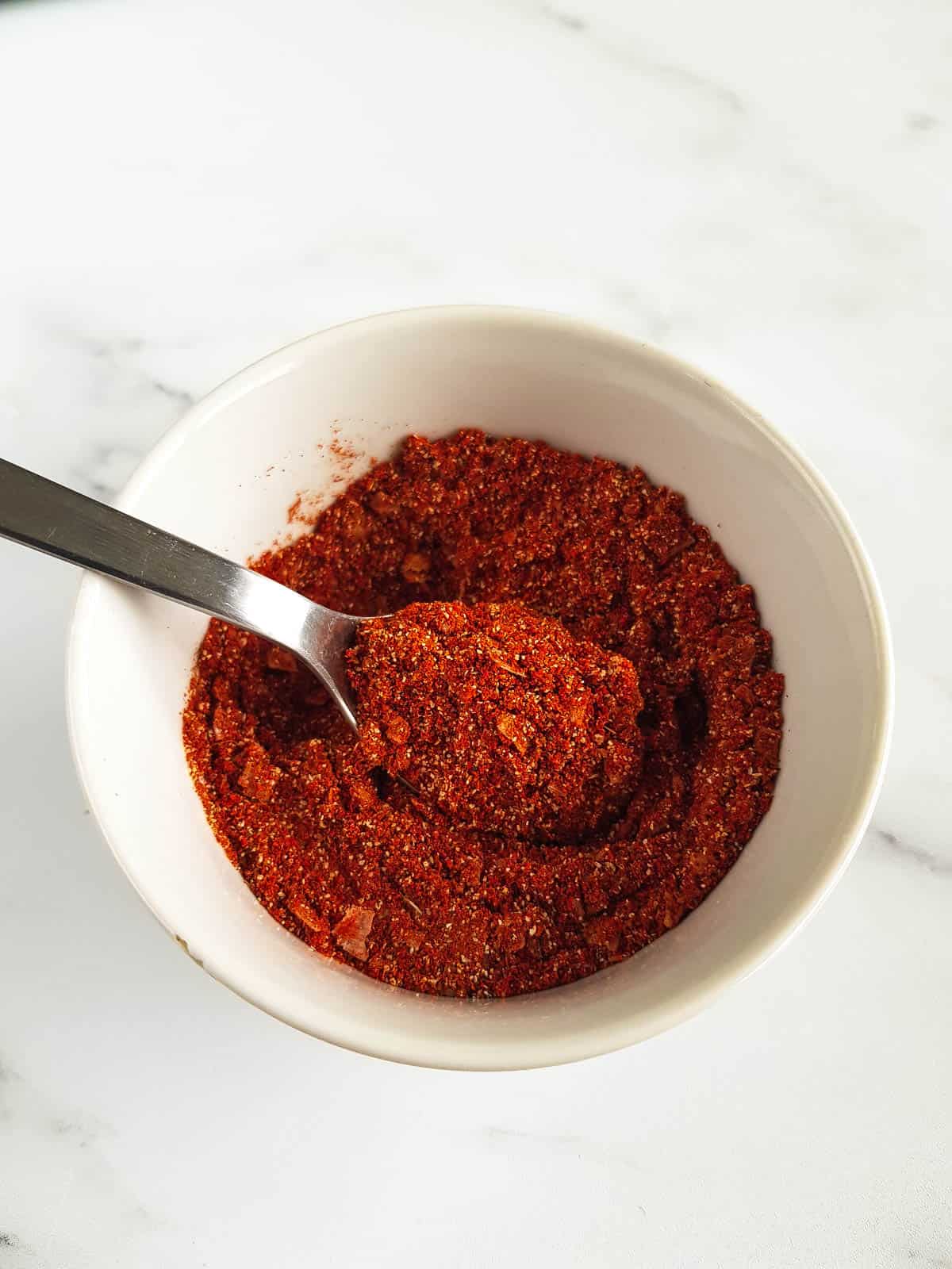 Pork seasoning in a bowl, with a spoon inserted.