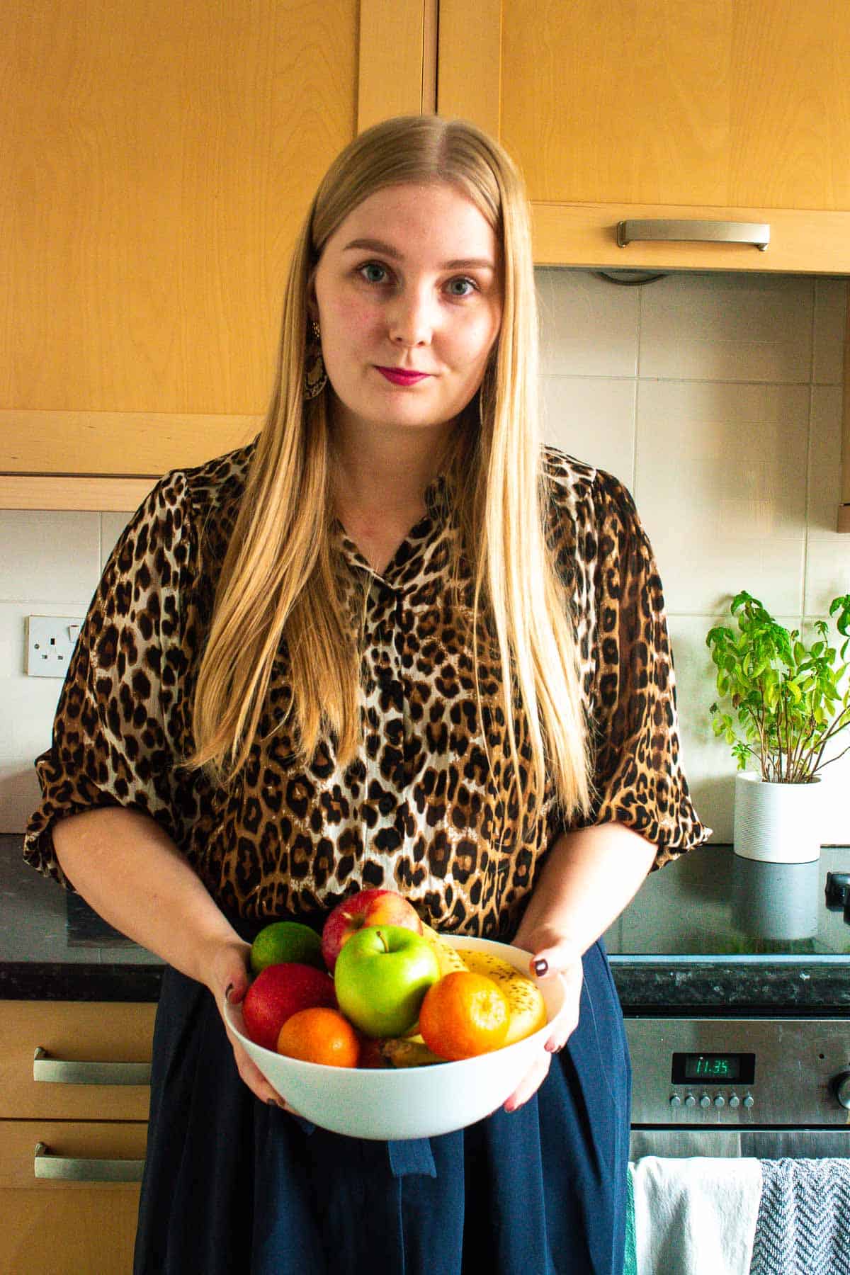 Picture of Tonje holding a bowl of fruit in a kitchen.