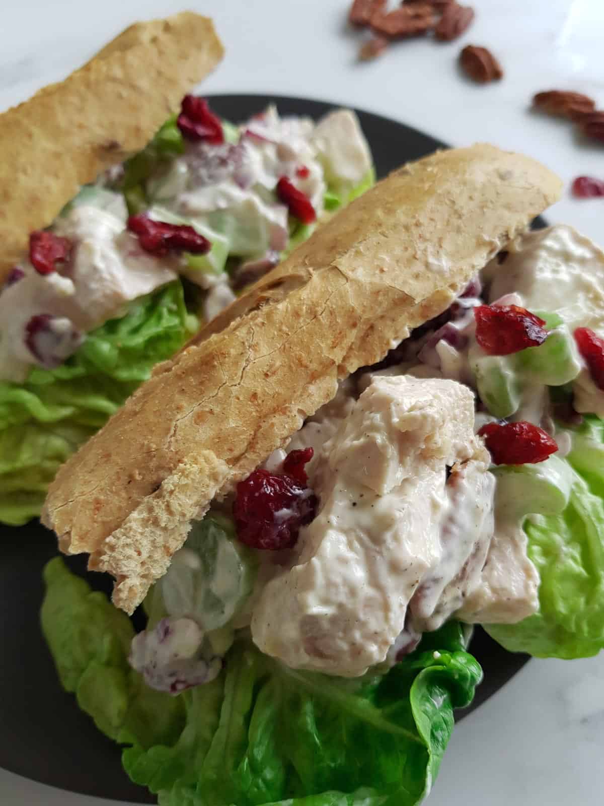 Two sandwiches filled with cranberry chicken salad and lettuce.