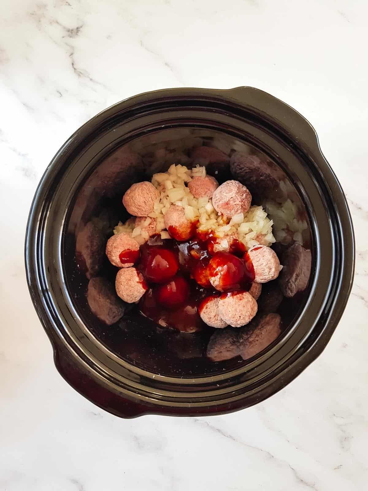 Frozen meatballs and BBQ sauce in a crock pot.