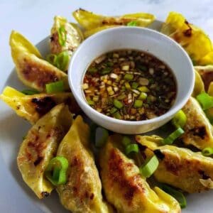 Gyoza sauce on a plate surrounded by gyozas.