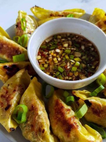 Gyoza sauce on a plate surrounded by gyozas.