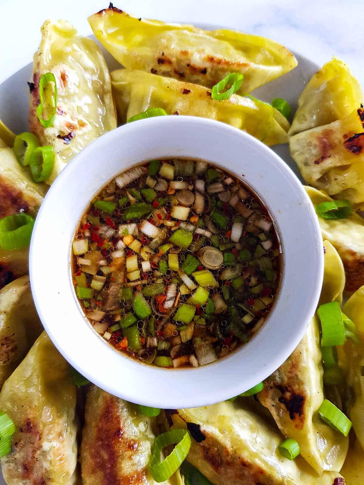 Gyoza sauce on a plate surrounded by gyozas.