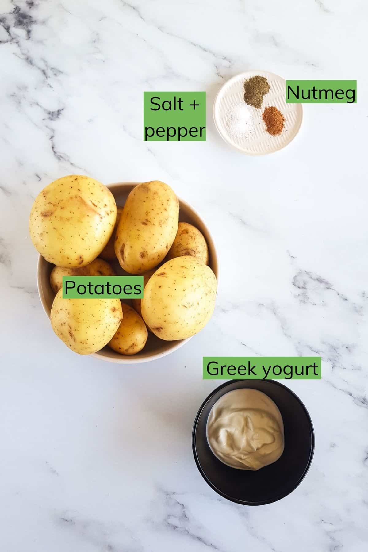 Potatoes, Greek yogurt, nutmeg, salt and pepper laid out on a table.