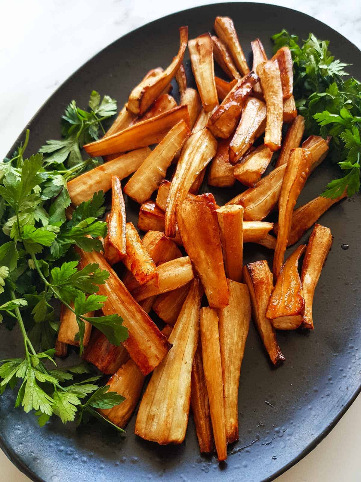 Honey roasted parsnips served with parsley garnish.