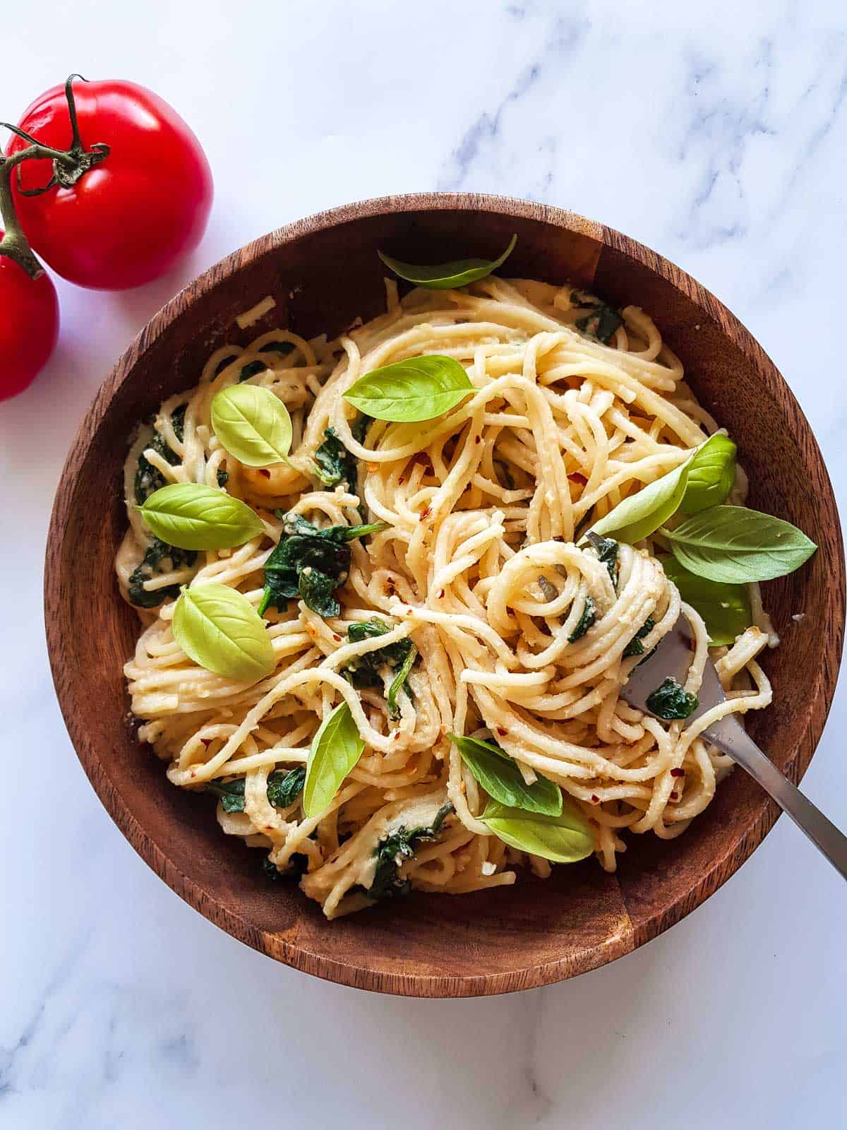 A fork lifting up a portion of hummus pasta.