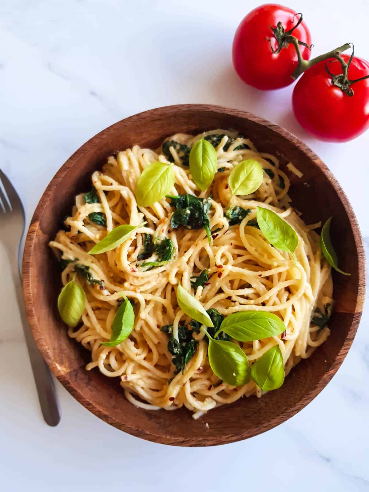 Hummus pasta in a bowl garnished with basil.
