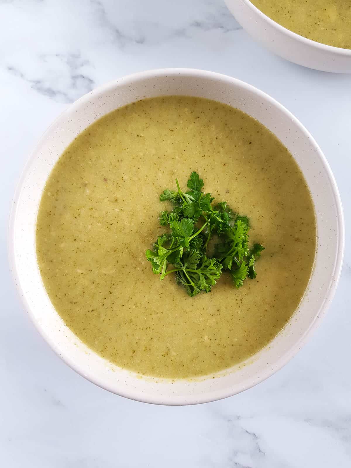 A white bowl with crockpot broccoli cheddar soup.