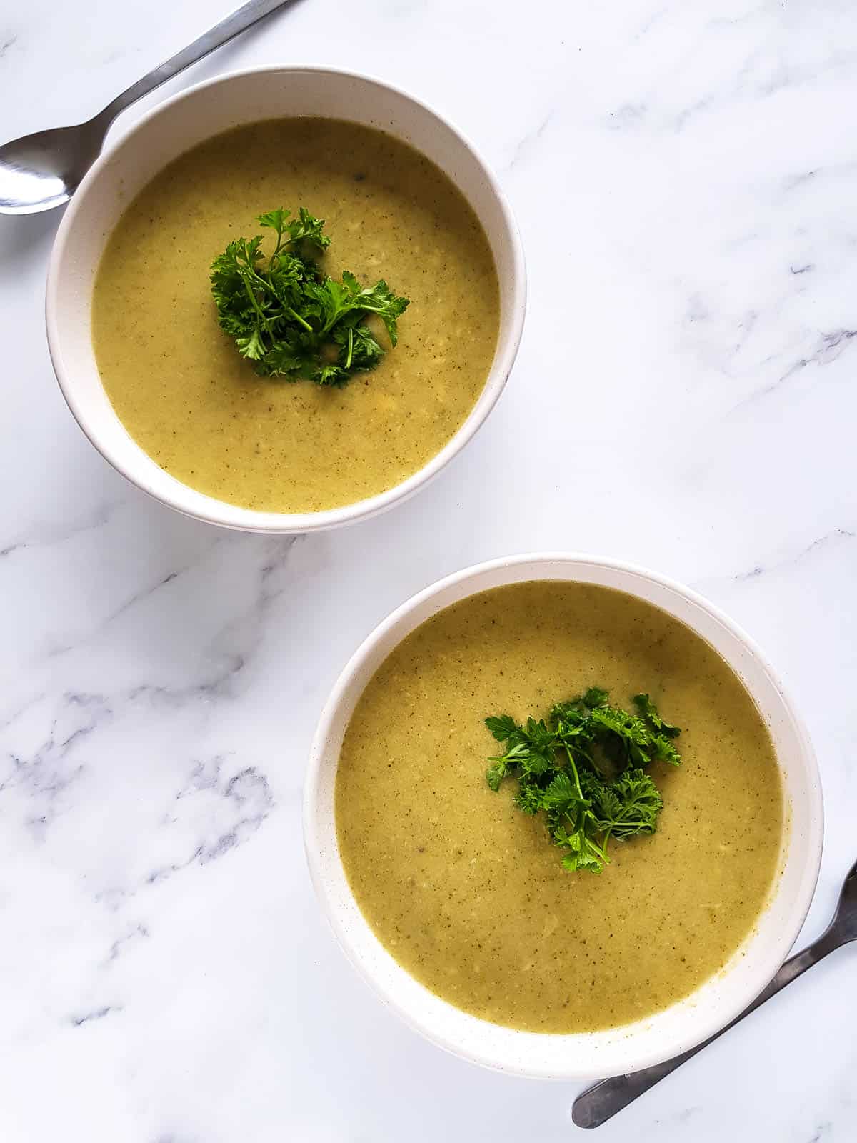 Two bowls of slow cooker cheddar soup on a table.