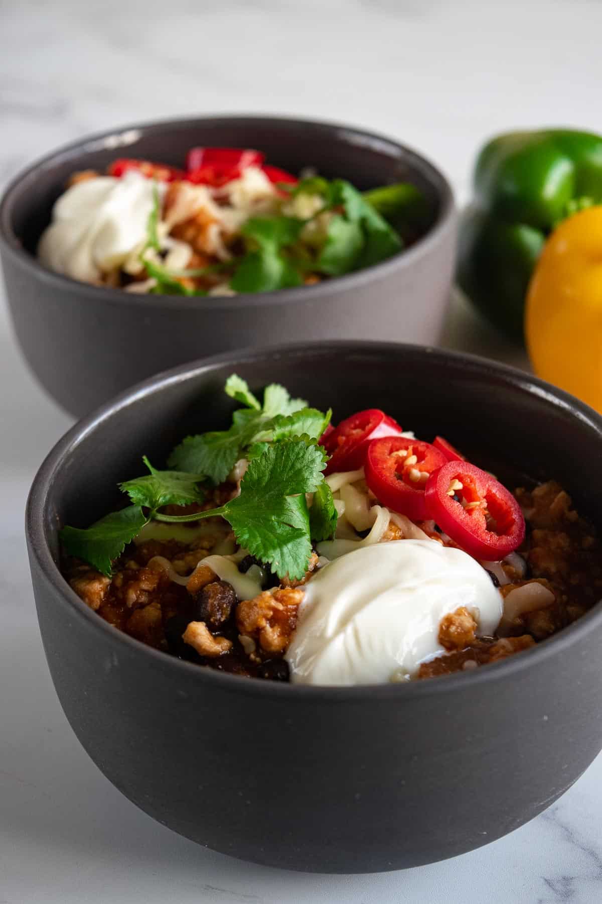 Two bowls of turkey sweet potato chili topped with chili, cilantro and yogurt.