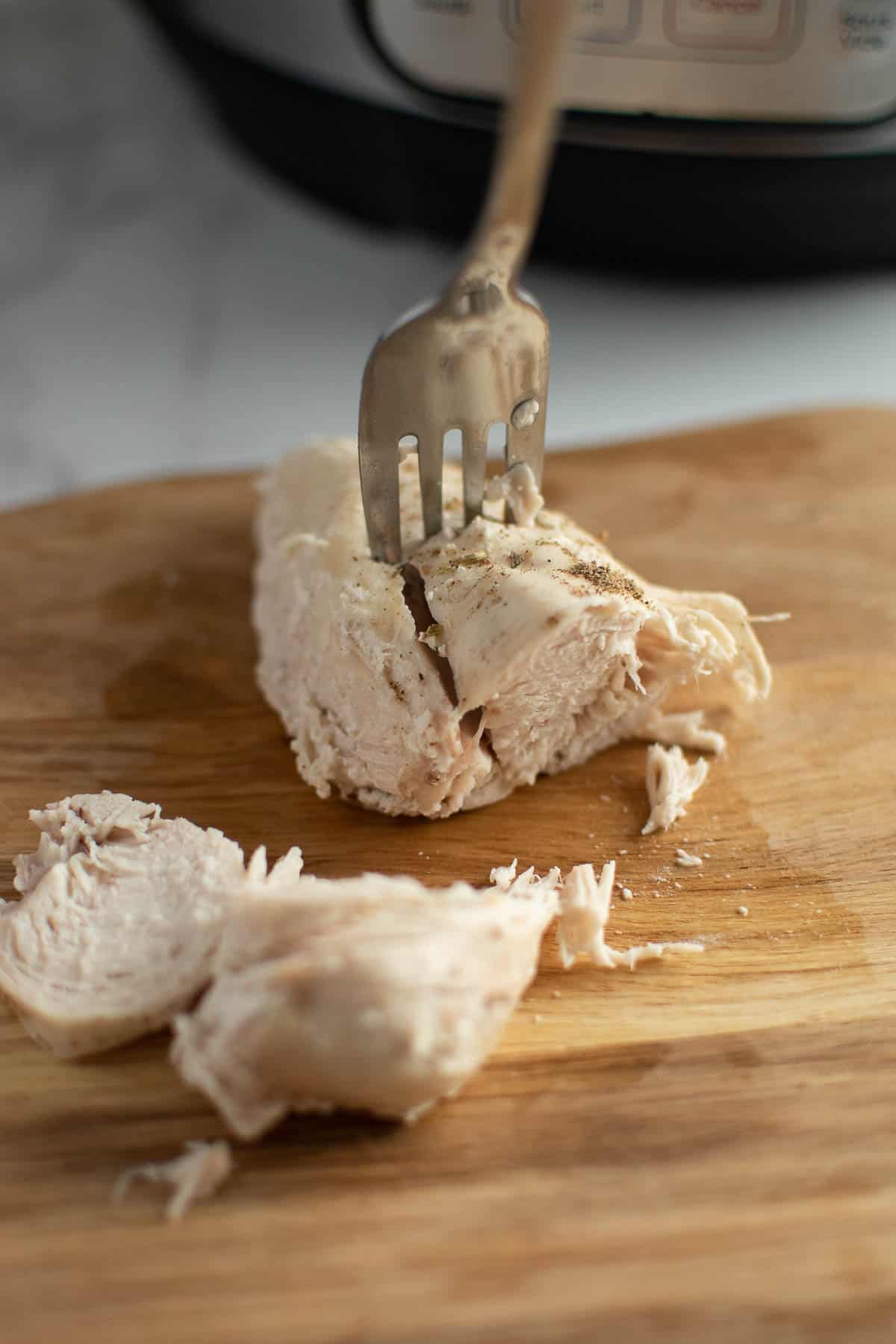 Cooked chicken breast pierced by a fork.