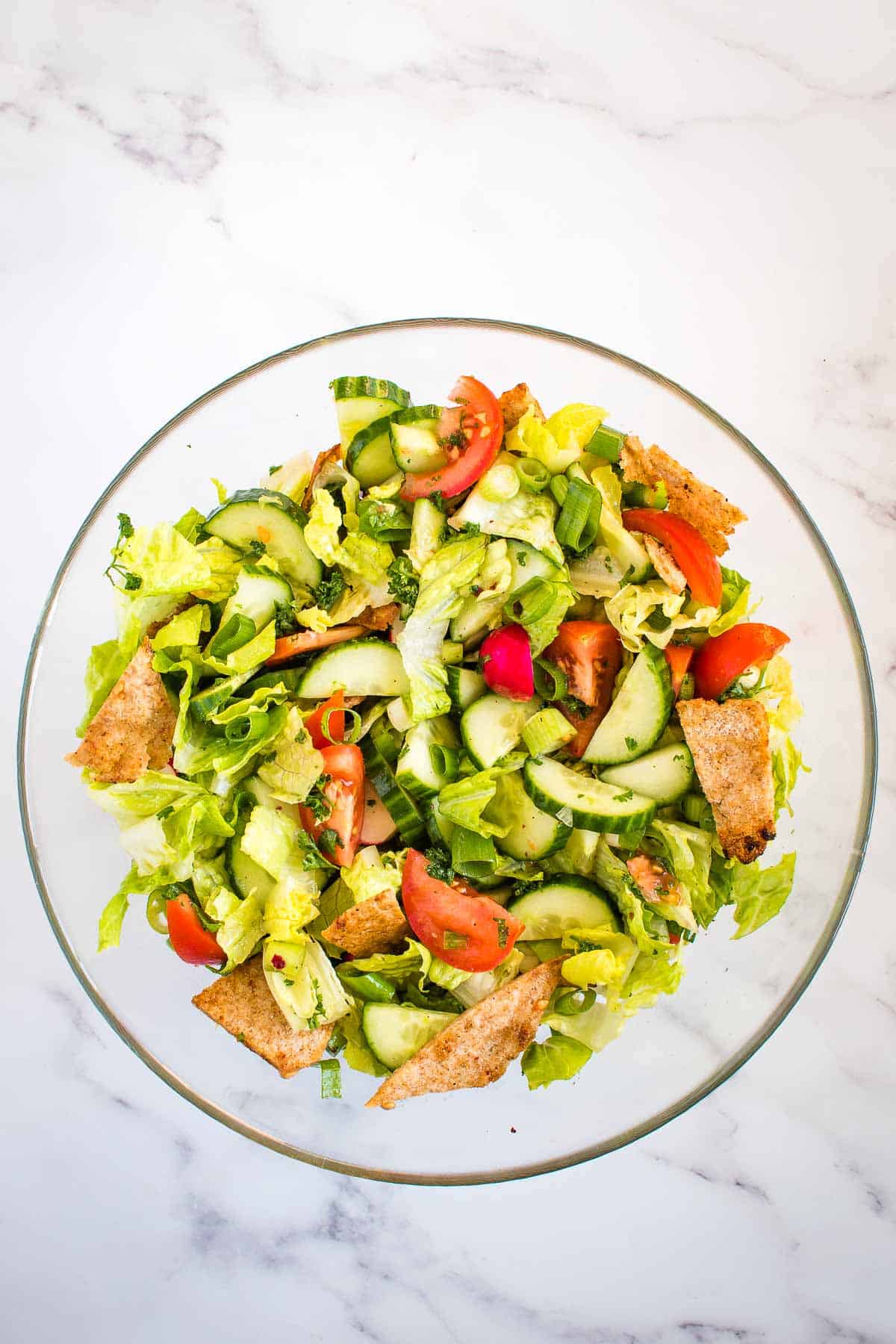 A bowl of Fattoush salad on a marble table.