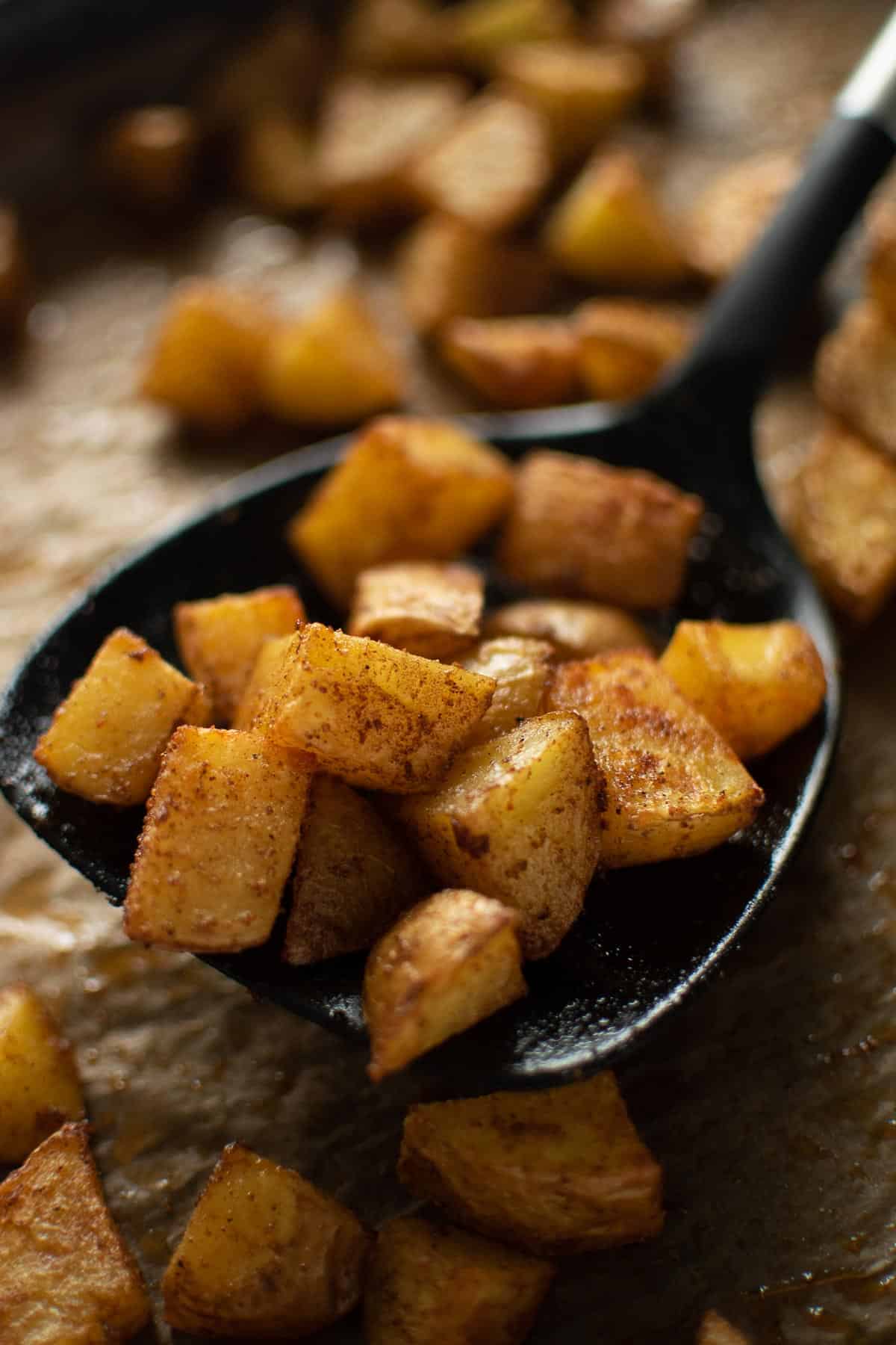 A spatula serving up some diced roast potatoes.