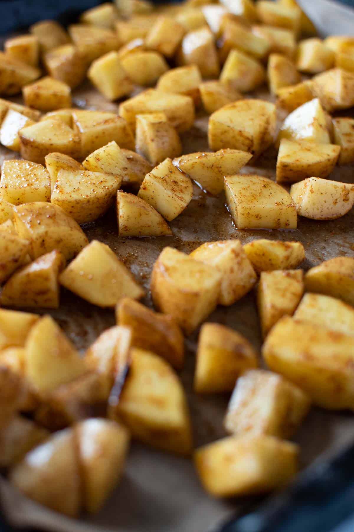 Seasoned diced potatoes on a sheet pan.